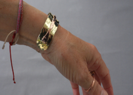 Bracelet cuivre et laiton martelé riveté vu de profil, porté au poignet, bijou artisanal fait main.