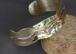 Bracelet martelé en laiton et cuivre ondulé, vue en diagonale, bijou artisanal aux reflets brillants.