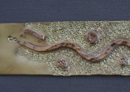 Plaque de laiton brute en cours de fabrication d’un bracelet, décorée d’un motif ondulé en cuivre rouge martelé et de détails texturés.