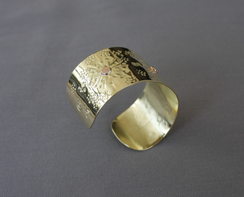 Détail du bracelet en laiton martelé soleil avec motifs poinçonnés et rivets cuivre