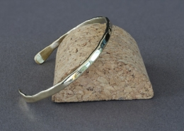 Bracelet fil en laiton martelé présenté sur un socle en liège, création artisanale Cuivre Island