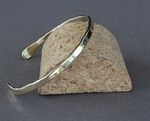 Bracelet fil en laiton martelé présenté sur un socle en liège, création artisanale Cuivre Island